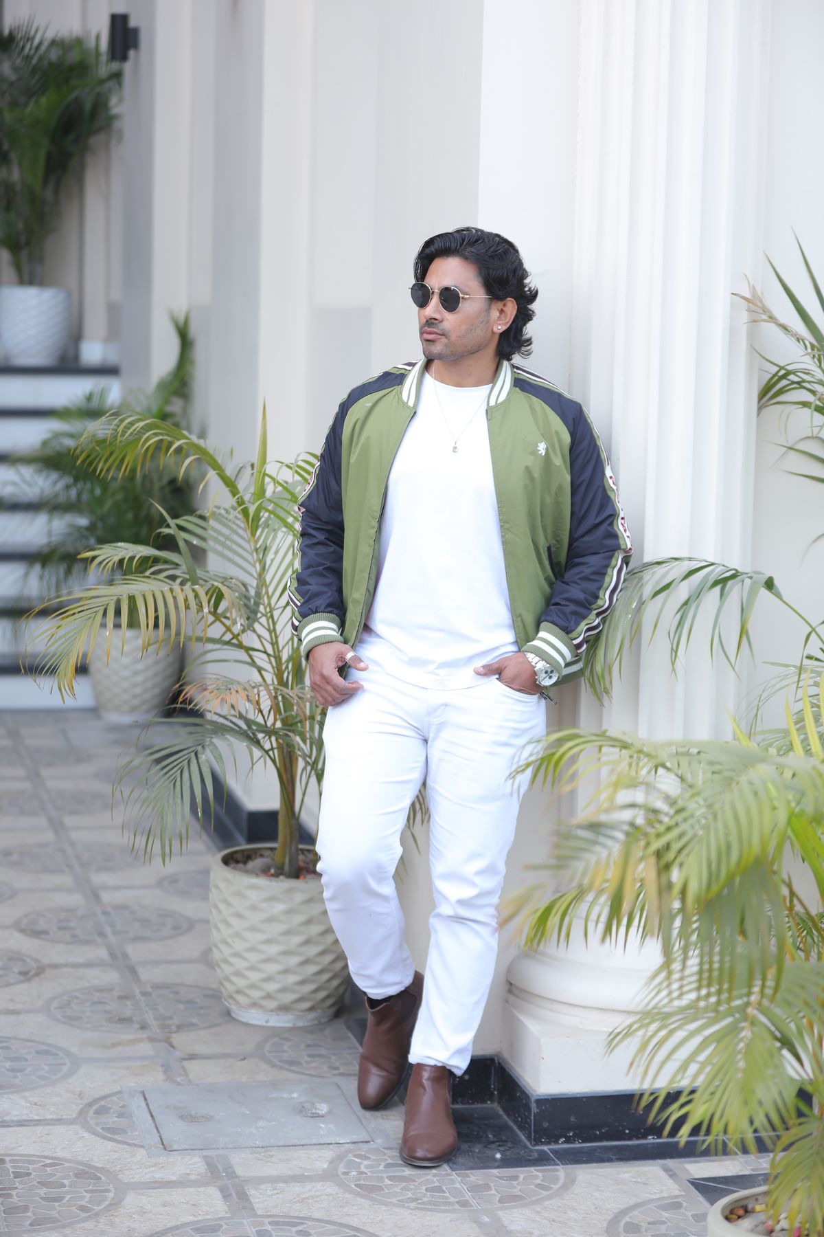 A green bomber jacket paired with a white top and white trousers.