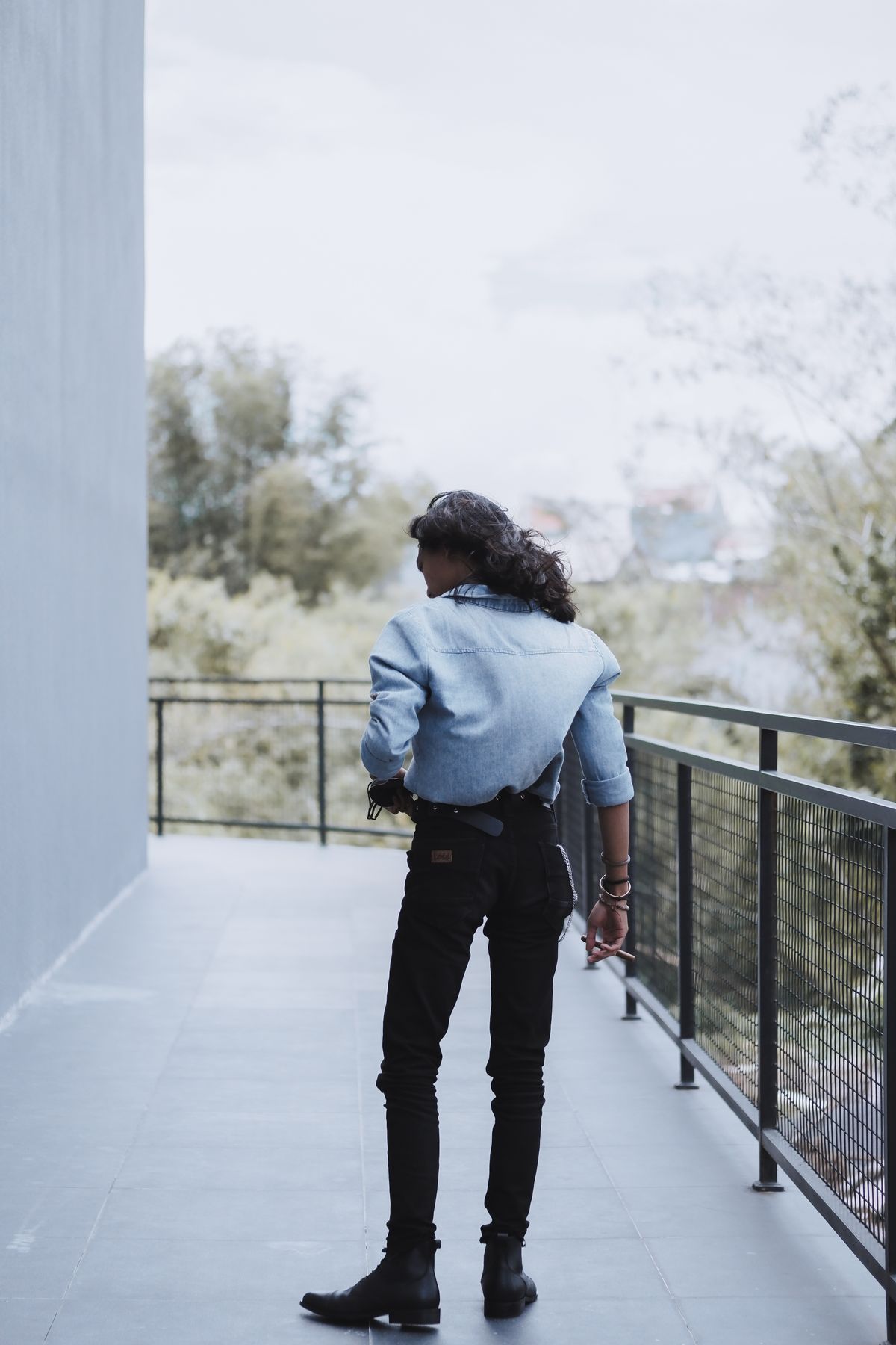 A cropped blue denim jacket worn with black trousers and boots.