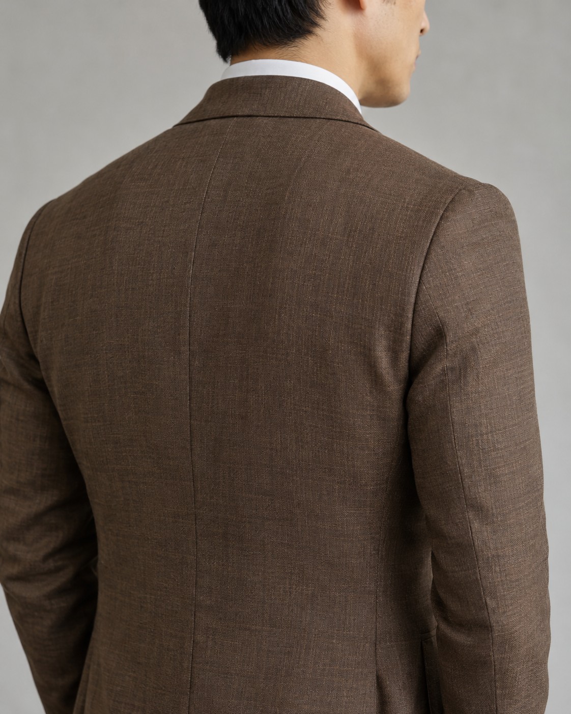 The shoulder and sleeve head of a brown tailored jacket.