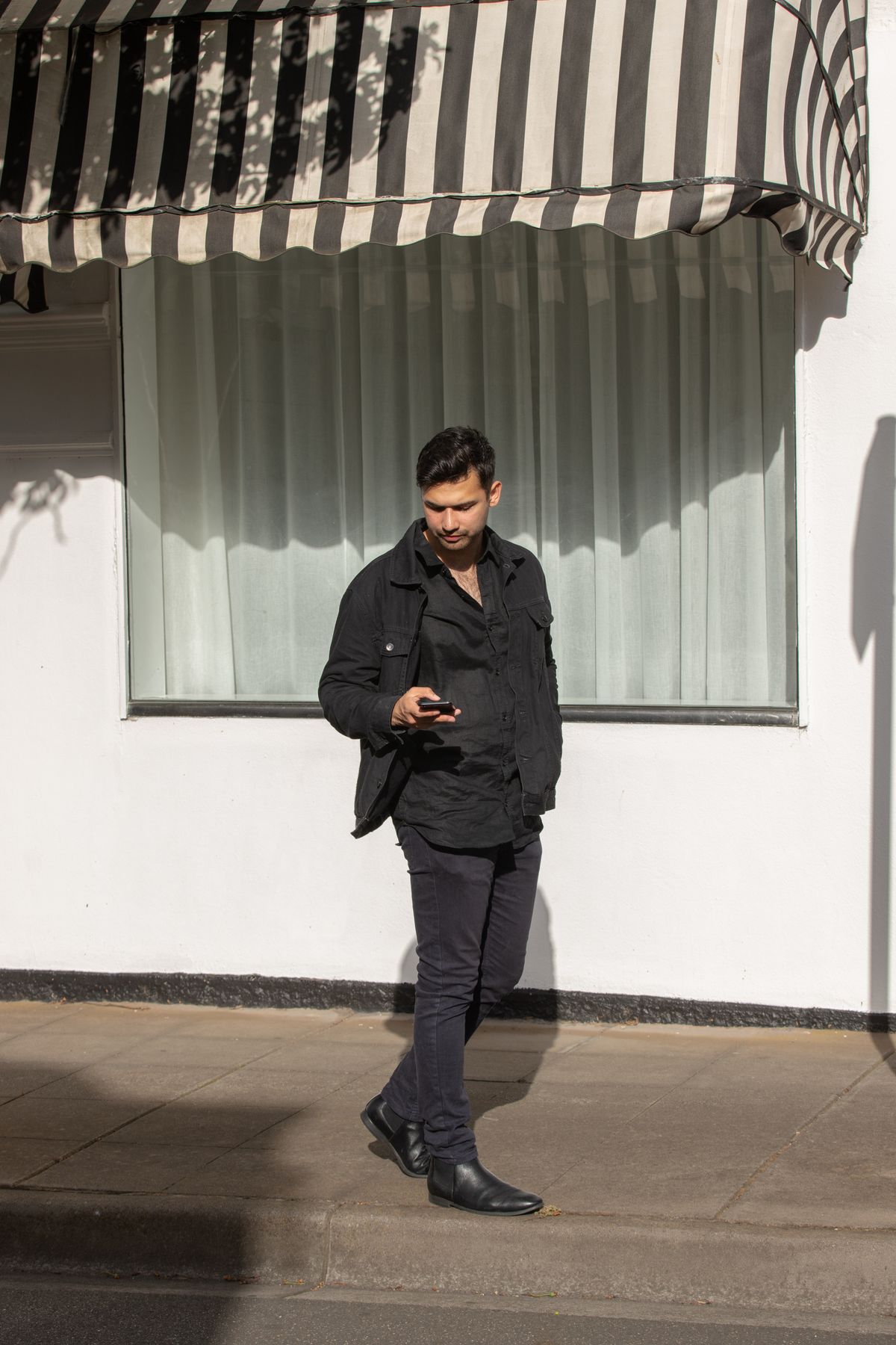 An all-black shirt, trousers and shoes outfit outdoors.