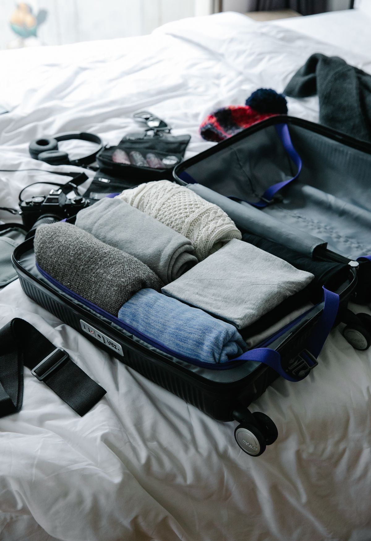 Folded clothes arranged in an open suitcase on a bed.