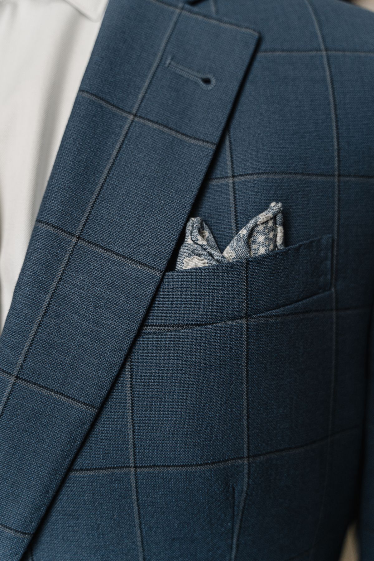 A patterned pocket square in a blue checked jacket.