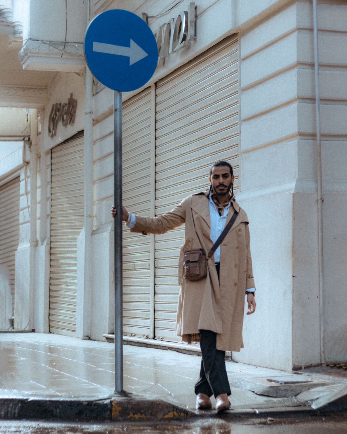 A beige trench-style coat worn on a wet city street.