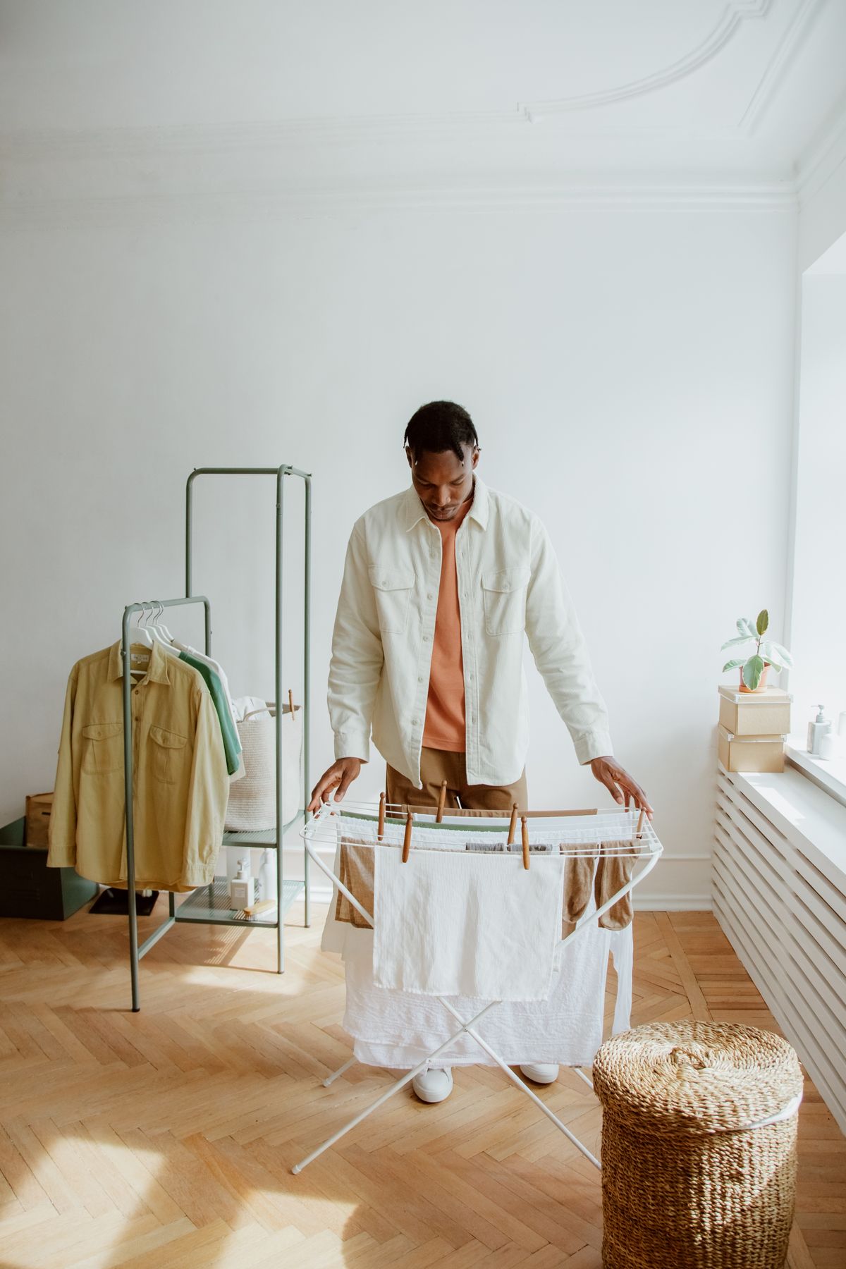 A man arranging light-coloured laundry on a drying rack.